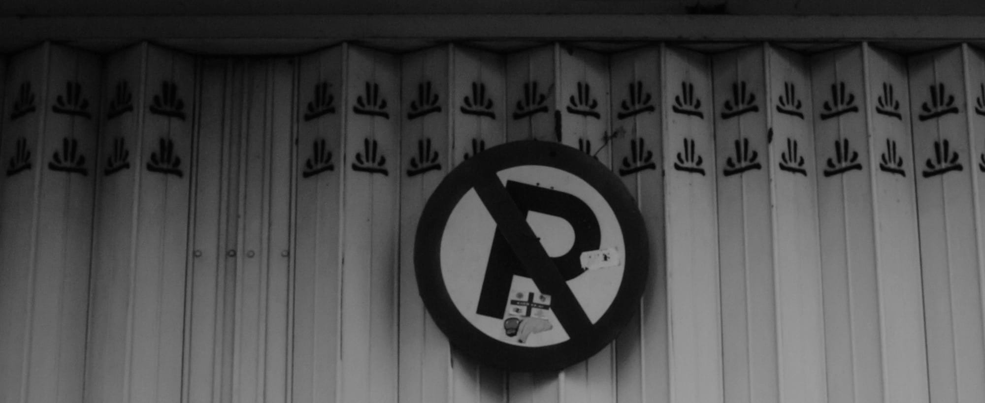 No parking sign on a closed metal gate.