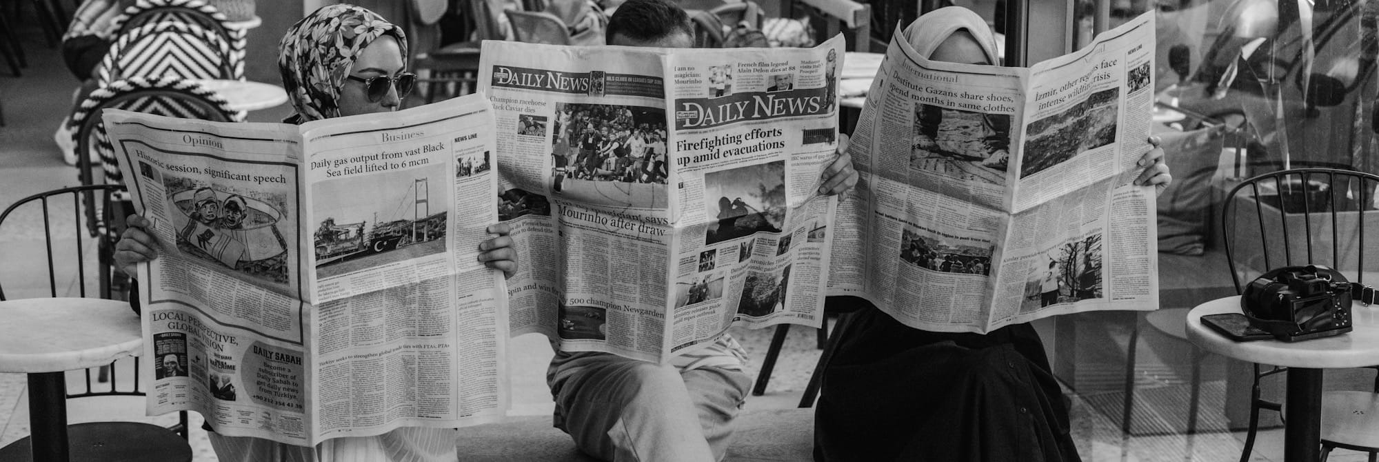 A man sitting on a bench reading a newspaper